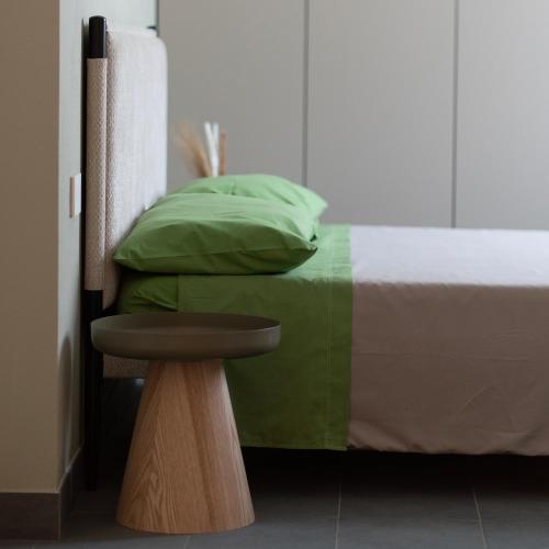 a bed with green pillows and a table next to it at Antica Corte Lugo in Lugo