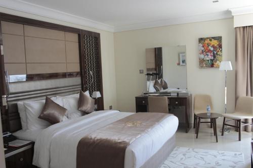 a bedroom with a large bed and a desk at Tio Sea Resort in Al Khor