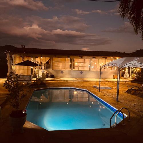 Una piscina frente a un edificio por la noche. en Lake House, en Morungaba