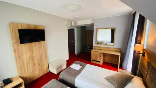 a hotel room with a bed and a television at Pensjonat Jurkowski Wellness & Spa in Ochotnica Dolna