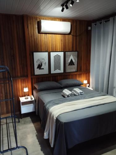 Un dormitorio con una cama en una pared de madera. en Casa balneário rincão sc, en Balneário do Rincão