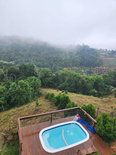 a plunge pool on a deck with a view of a forest at Chalé dos Manacás Duplex in Venda Nova do Imigrante