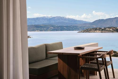 a living room with a table and a view of the water at JW Marriott Crete Resort & Spa in Marathi