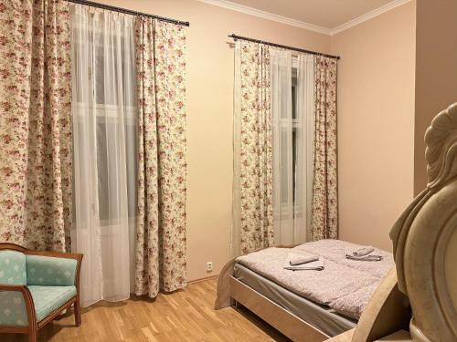 a bedroom with a bed and a chair and curtains at Salve Teplice in Teplice