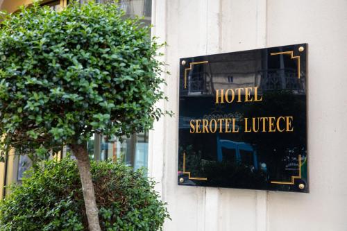 a sign on the side of a hotel with a tree at Hôtel Serotel Lutèce in Paris