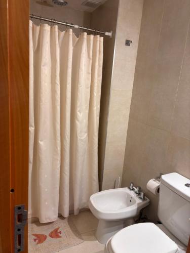 Un baño con inodoro y cortina de ducha. en Departamento Austral II, en Ushuaia