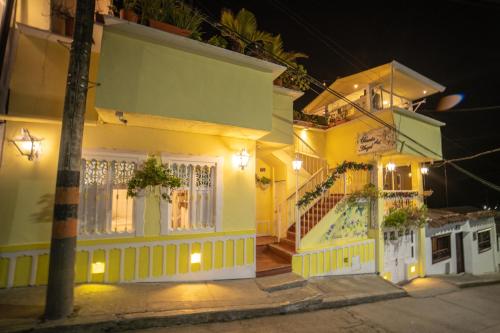 a yellow house with a porch and stairs at night at Posada del Angel in Salento