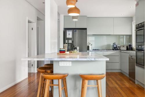 a kitchen with white cabinets and a counter with stools at Alpine Snow Angels Retreat in Jindabyne