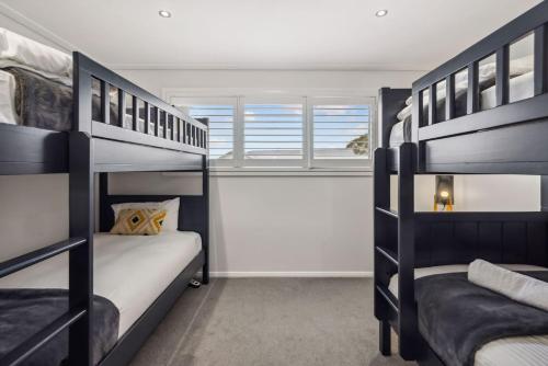 two bunk beds in a room with a window at Alpine Snow Angels Retreat in Jindabyne