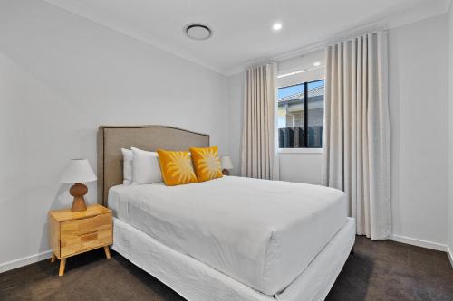a white bedroom with a bed and a window at Mi Casa Su Casa - Brand New Home In Moss Vale in Moss Vale
