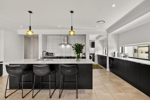 a kitchen with a large island with bar stools at Mi Casa Su Casa - Brand New Home In Moss Vale in Moss Vale