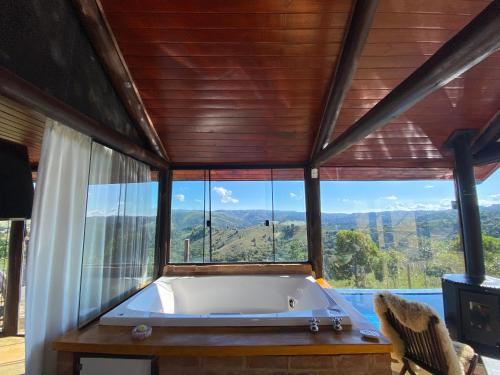 a large tub in a room with a large window at Chalé Mirante Vista Privilegiada - o mais alto do Brasil in Campos do Jordão