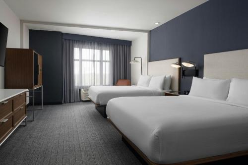 a hotel room with two beds and a television at Courtyard by Marriott Dallas DFW Airport North/Grapevine in Grapevine