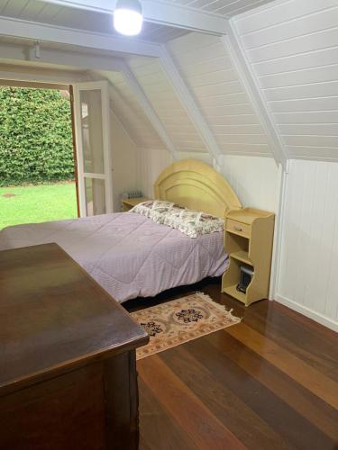 a bedroom with a bed and a desk and a window at o sossego e aqui in Campos do Jordão