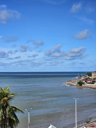 a view of the ocean from a beach with a palm tree at FLAT BLUE SUNSET in João Pessoa
