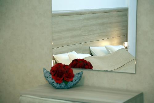 a mirror with a bowl of red flowers in front of a bed at Parliament Square in Bucharest