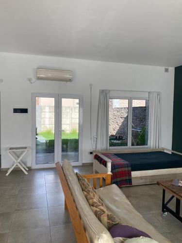 a bedroom with a bed and a couch and windows at Jencquel Home in Coronel Suárez