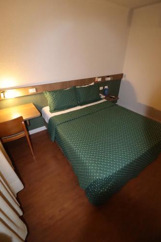 a bedroom with a green bed and a table at Strassen Hotel in Goiânia