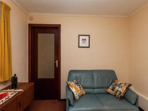 a living room with a blue couch and a door at Cottage Near Durbuy Forest in Barvaux
