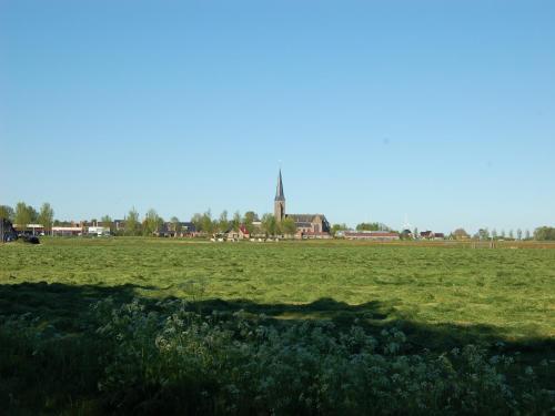 a large field of grass with a church in the background at Apartment in Workum near IJsselmeer Beach in Workum
