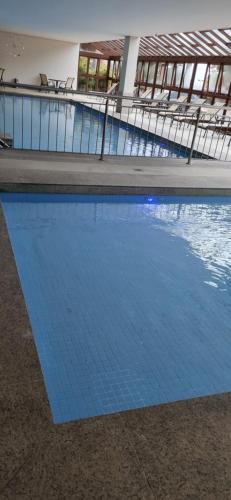 a swimming pool with blue water in a building at Flat Condomínio Vista Azul - Pedra Azul in Pedra Azul