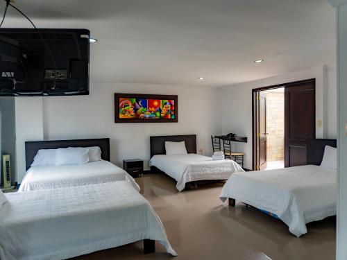 a bedroom with two beds and a flat screen tv at Hotel Andinos Plaza Pitalito in Pitalito