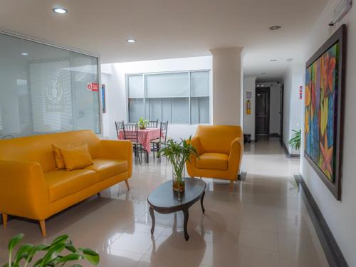 a living room with two yellow couches and a table at Hotel Andinos Plaza Pitalito in Pitalito