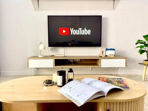 a living room with a tv and a table with a book at Ezyhouz # Luxury 3Bedroom Seaview Balcony IMAGO TheLoftB KotaKInabalu CIty10Pax in Kota Kinabalu
