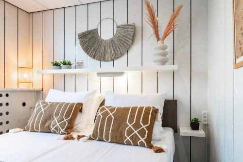 a bedroom with a bed with white sheets and pillows at Stylish Suite Steps To Shore in Zoutelande