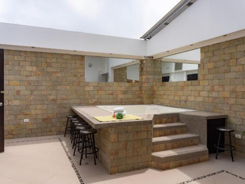 an outdoor kitchen with a tub and bar with stools at Hotel Andinos Plaza Pitalito in Pitalito