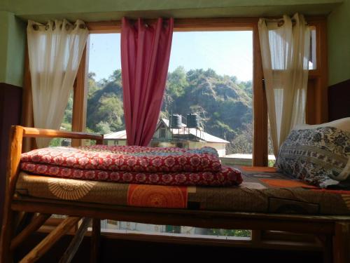 a bed in a room with a large window at The Sigiriya Old manali in Manāli