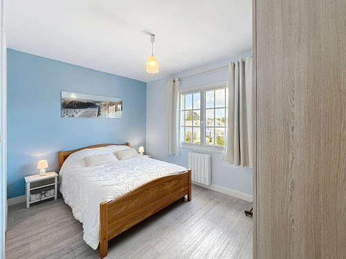 une chambre avec un lit et un mur bleu dans l'établissement Appartement cosy à 100m de la plage et des commerces, centre de Jullouville - FR-1-361-37, à Jullouville