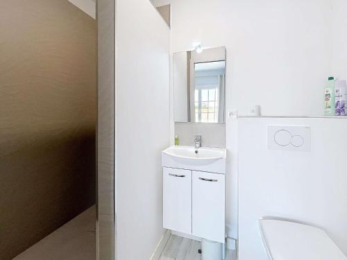une salle de bain blanche avec un lavabo et un miroir dans l'établissement Appartement cosy à 100m de la plage et des commerces, centre de Jullouville - FR-1-361-37, à Jullouville