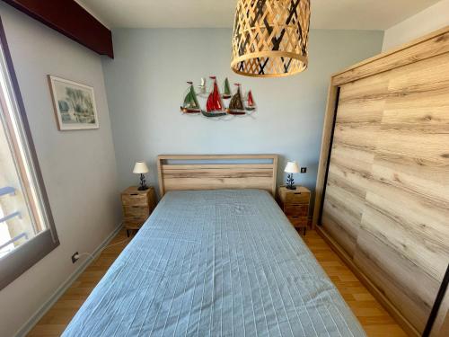une chambre avec un lit et une porte en bois avec des voiles sur le mur dans l'établissement Face Océan : T3 au 9ème avec Balcon-Terrasse, Centre Plage et Ville, Tout Confort - FR-1-92-645, à Les Sables-dʼOlonne