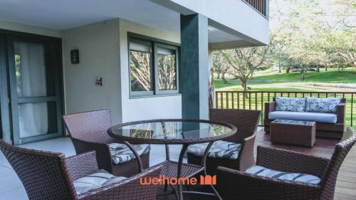 a patio with a glass table and chairs on a porch at Refugio com Lazer Completo em Gravata in Gravatá