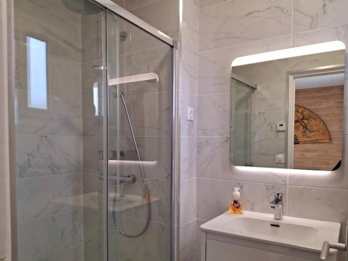 une salle de bain avec douche et lavabo dans l'établissement À 300 m de la plage, charme et tranquillité à Merville-Franceville - FR-1-788-66, à Merville-Franceville-Plage