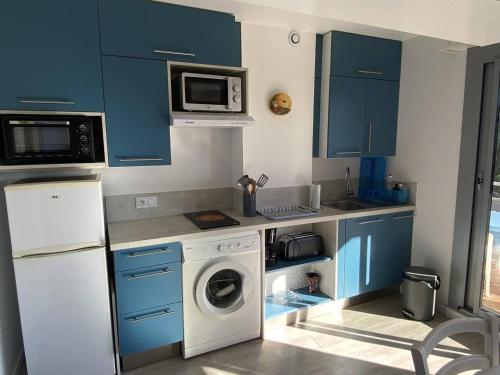 une cuisine avec des armoires bleues et une machine à laver dans l'établissement Charmant Deux-Pièces Climatisé à Canet-Plage - FR-1-750-87, à Canet
