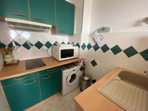 La cuisine est équipée de placards verts et d'un four micro-ondes. dans l'établissement Appartement 2 pièces, terrasse face mer, parking - FR-1-750-91, à Canet