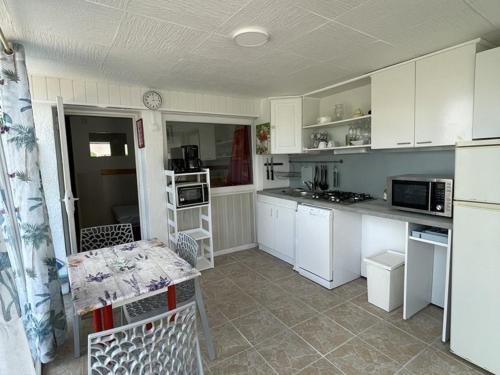 une cuisine avec des armoires blanches et une table à l'intérieur dans l'établissement Studio 2/3 personnes près du lac avec animaux acceptés et parking - FR-1-822-18, à Esparron-de-Verdon
