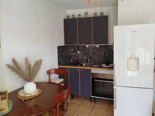 une cuisine avec une table et un réfrigérateur blanc dans l'établissement Charmant T2 avec Clim, Parking, et WiFi à Bormes - FR-1-610-108, à Bormes-les-Mimosas