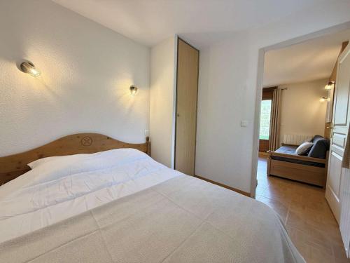 une chambre avec un grand lit blanc et un canapé dans l'établissement Appartement cosy à Flumet avec parking et piscine - FR-1-603-121, à Flumet