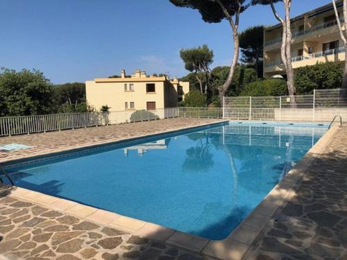une grande piscine bleue devant une maison dans l'établissement Appartement 2P à Bormes-les-Mimosas avec accès piscine - FR-1-251-859, à Bormes-les-Mimosas