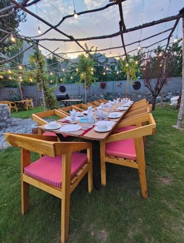 a wooden table in a yard with chairs and lights at Das-e-Basi in Gilgit