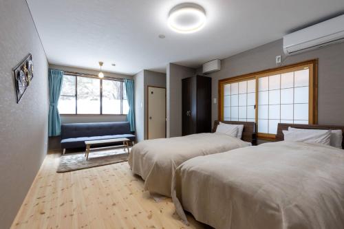 a hotel room with two beds and a couch at 御宿こだま in Matsumoto