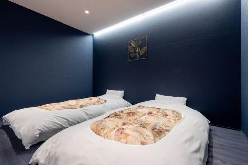 two beds in a room with blue walls at 御宿こだま in Matsumoto