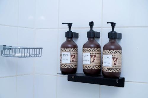 three bottles of liquid on a shelf in a bathroom at Sailors Beach Fiji in Nadi