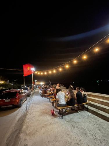a group of people sitting on benches at night at Lê Huỳnh Guest House Family in Ke Ga