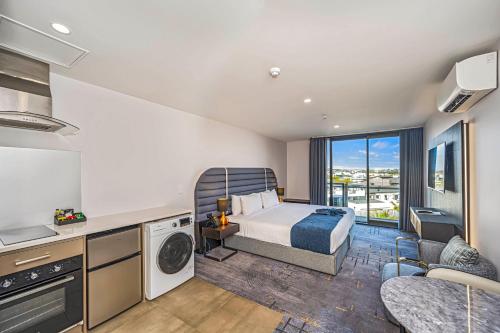 a bedroom with a bed and a kitchen with a balcony at Marsden Suites Albany in Albany