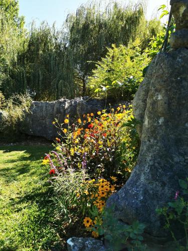 a garden with colorful flowers and a large rock at Karstaway Haven in Takaka