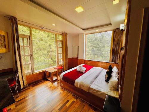 a bedroom with a bed and two large windows at Staynest BNB in city Centre - 3 BHK apartments - PRIVATE PARKING - BALCONY VIEW in Shimla